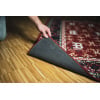 Drum rug being placed on wooden floor by a hand.