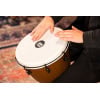 Close-up of a person playing a hand drum, focusing on hands and drum surface.