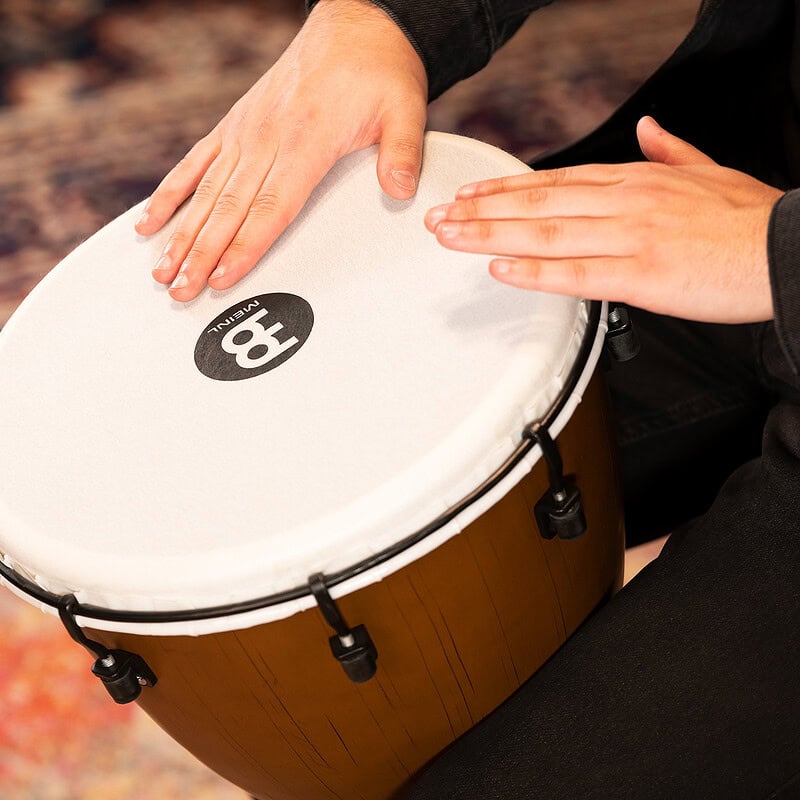 Close-up of a person playing a hand drum, focusing on hands and drum surface.