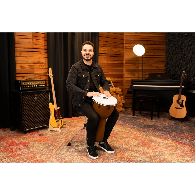 Young man playing conga drum in a professional music studio with guitars and piano.