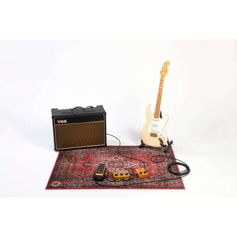 Electric guitar with amplifier and effects pedals on a rug.
