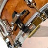 High-quality wooden snare drum with chrome hardware and black strap detail.