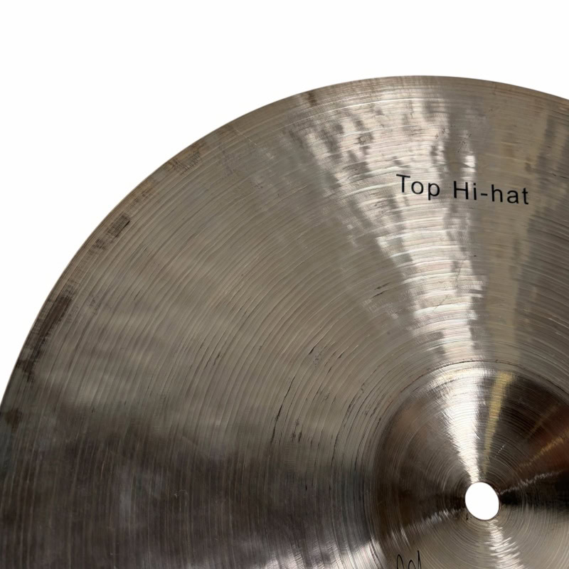Close-up of a hi-hat cymbal with "Top Hi-hat" label, used in drum kits for percussion.