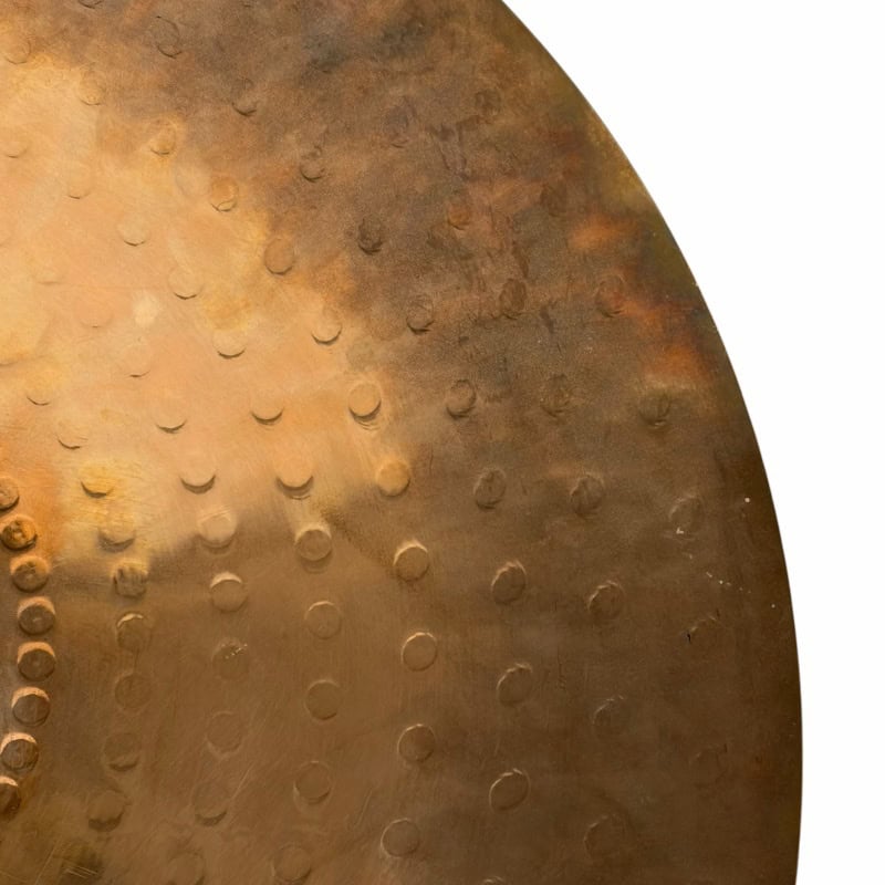 Vintage cymbal with detailed rivets, used in percussion and drum kits.