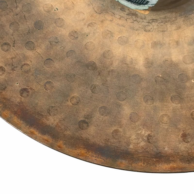 Vintage cymbal with visible hammer marks and patina, showcasing its aged and textured surface.