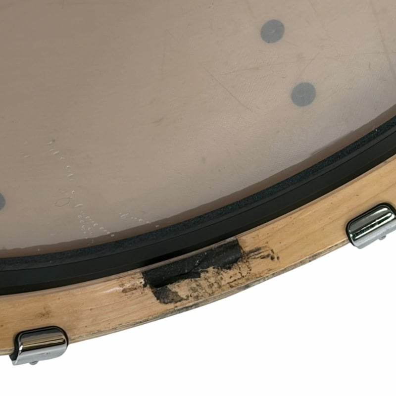 Close-up of a drum with a damaged wooden rim and worn surface.