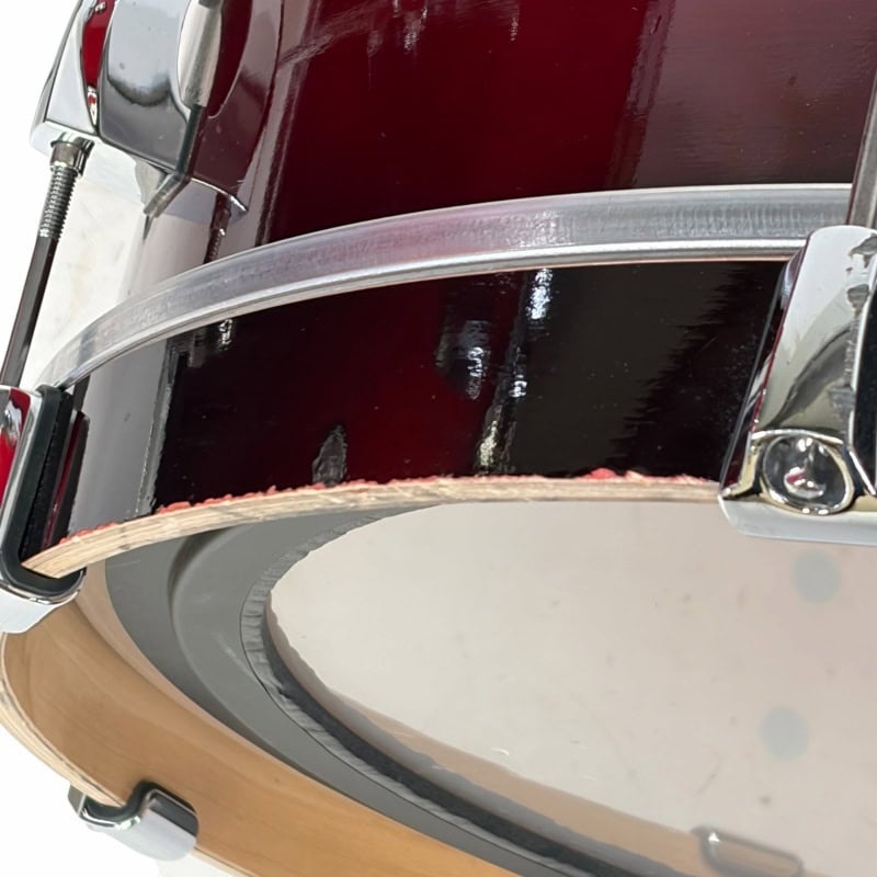 Close-up of a high-quality drum kit with red and black shells and chrome hardware.