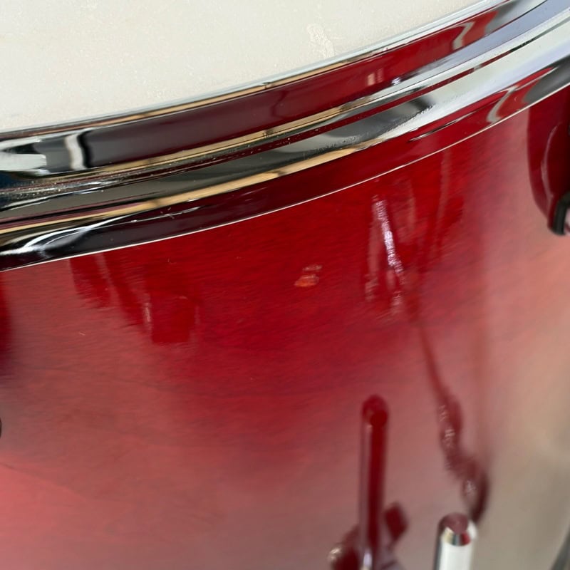 Close-up of a red drum with chrome hardware, highlighting quality percussion equipment.