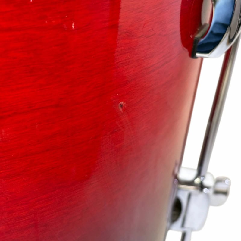 Close-up of a red drum with hardware, highlighting drum finish and details.