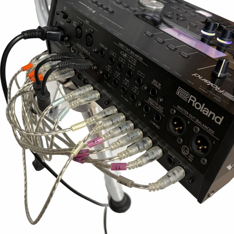 Roland audio mixer with multiple cables for professional drumming sound setup.