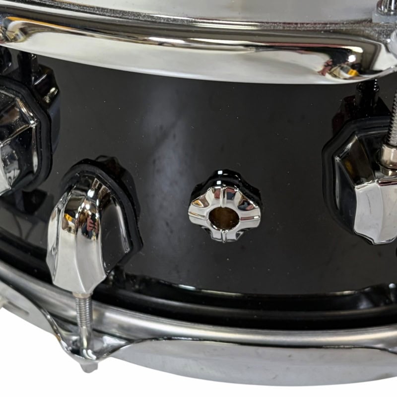 Close-up of a black drum kit with chrome hardware and drum lugs.