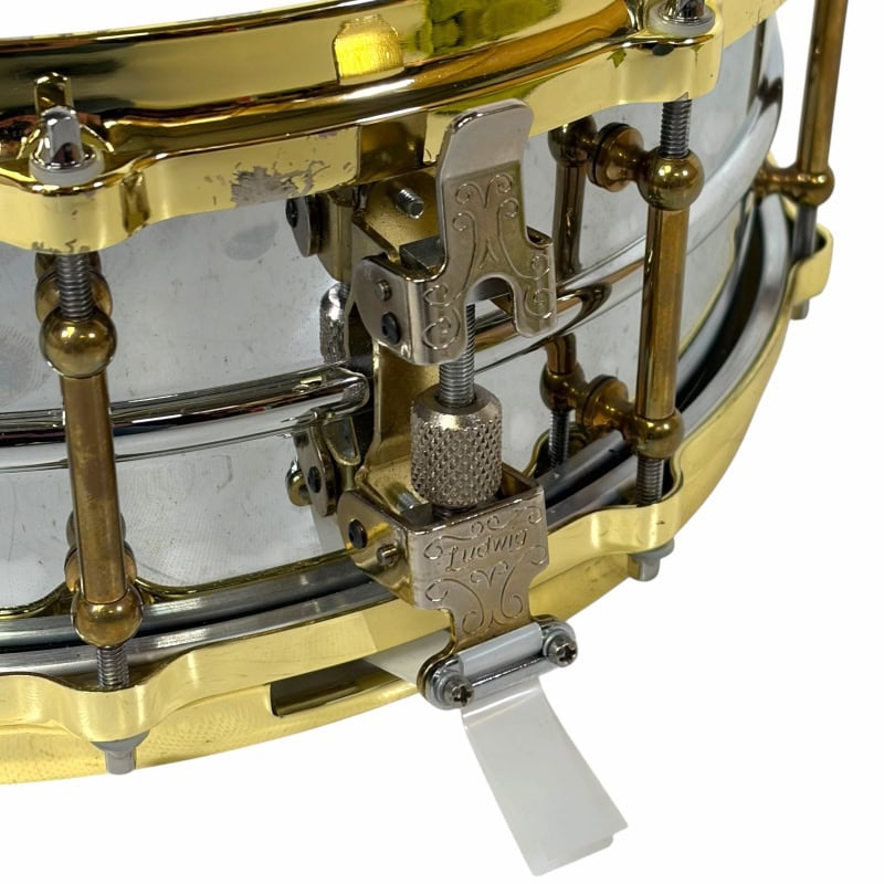 Close-up of a professional snare drum with gold hardware and tuning mechanisms.