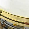 Close-up of a shiny gold drum snare with detailed hardware.