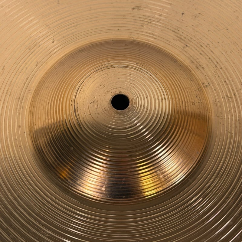 Close-up of a shiny cymbal with concentric circles, representing professional drumming equipment.