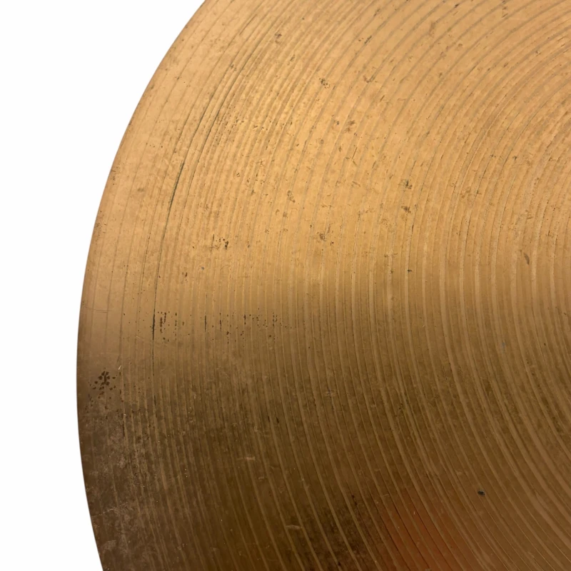 Close-up of a vintage drum cymbal with detailed grooves and patina.