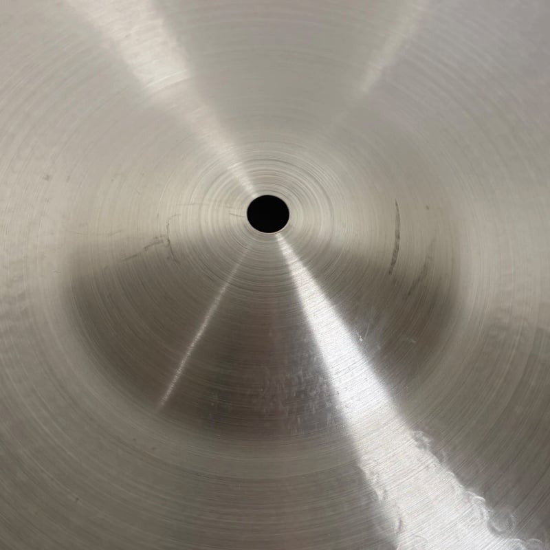 Close-up of a metal snare drum surface with concentric circles and central hole.