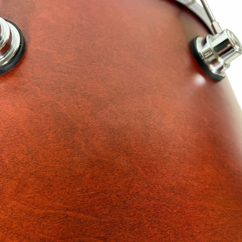 Close-up of a wooden drum shell with chrome hardware, showcasing craftsmanship and sound quality.