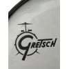 Close-up of Gretsch logo on drum with drumstick in background.