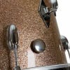 Close-up of a glittery brown drum shell with hardware details.