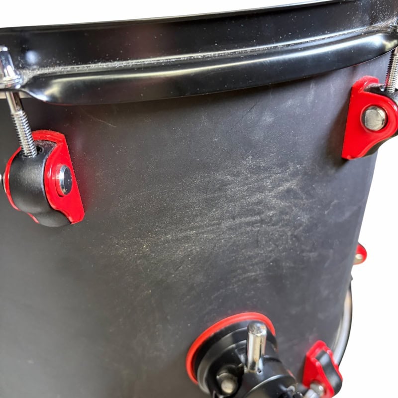 Close-up of a black drum with red hardware, part of a professional drum kit.