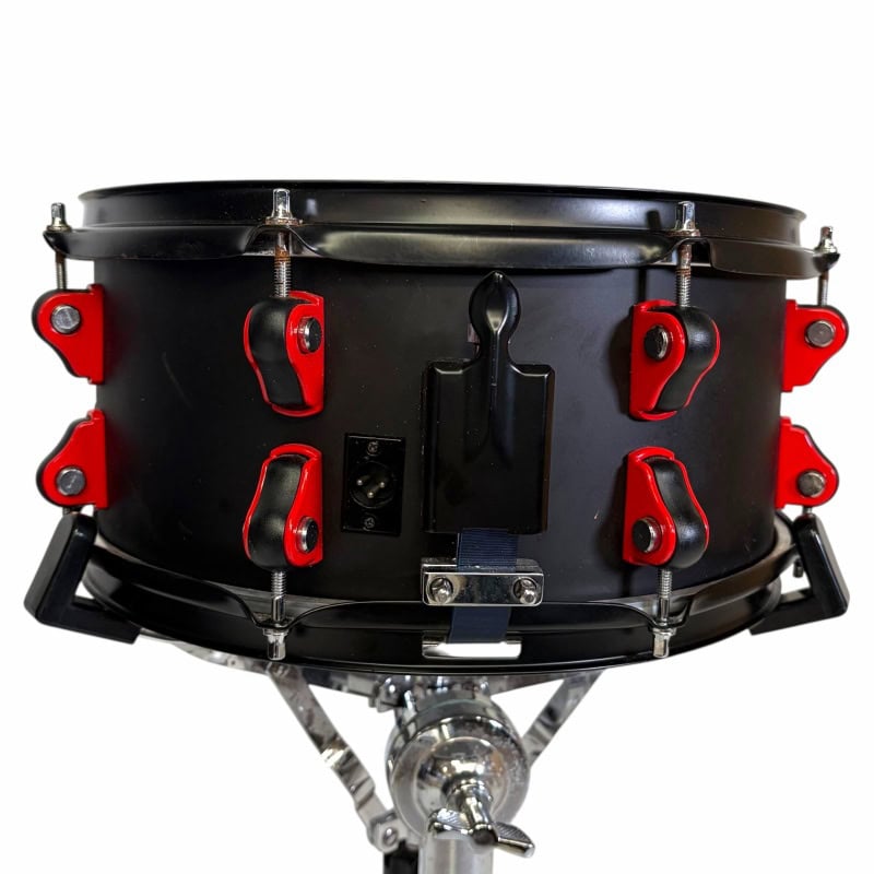 Black snare drum with red lugs, mounted on a stand, for professional drumming.