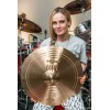 Female drummer holding a large cymbal in a professional drum studio.