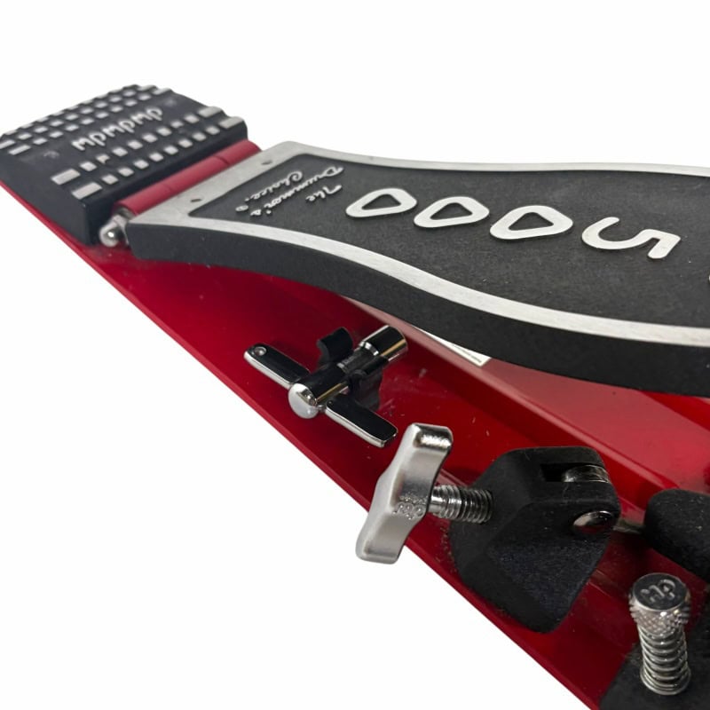 Close-up of DW 5000 single bass drum pedal with black footboard and red frame.