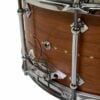Close-up of a wooden snare drum with metal hardware and drumsticks.