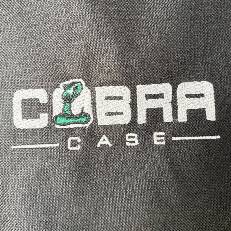 Cobra drum case logo with snake illustration on black fabric.