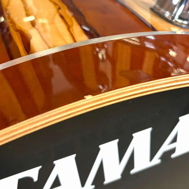 Close-up of a polished wooden guitar body with branding detail.