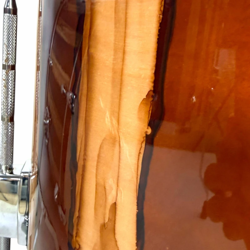 Close-up of a wooden drum shell with drum hardware, showcasing professional drum equipment.