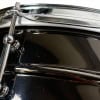 Close-up of a shiny steel snare drum with chrome hardware.