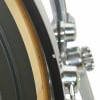 Close-up of drum kit hardware and shell with detailed focus on drum rim and tuning pegs.