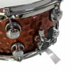 Close-up of hammered steel snare drum with chrome hardware and tuning knobs.