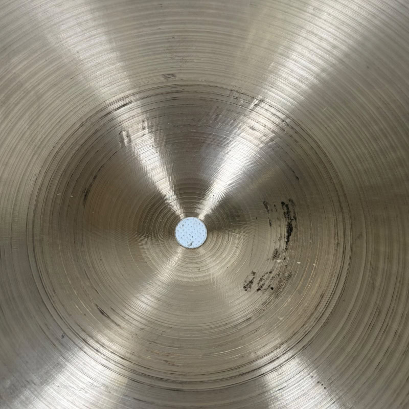 Close-up of a metallic cymbal with concentric circles and a central hole.