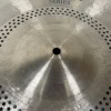 Close-up of a silver ride cymbal with perforations and a central hole.
