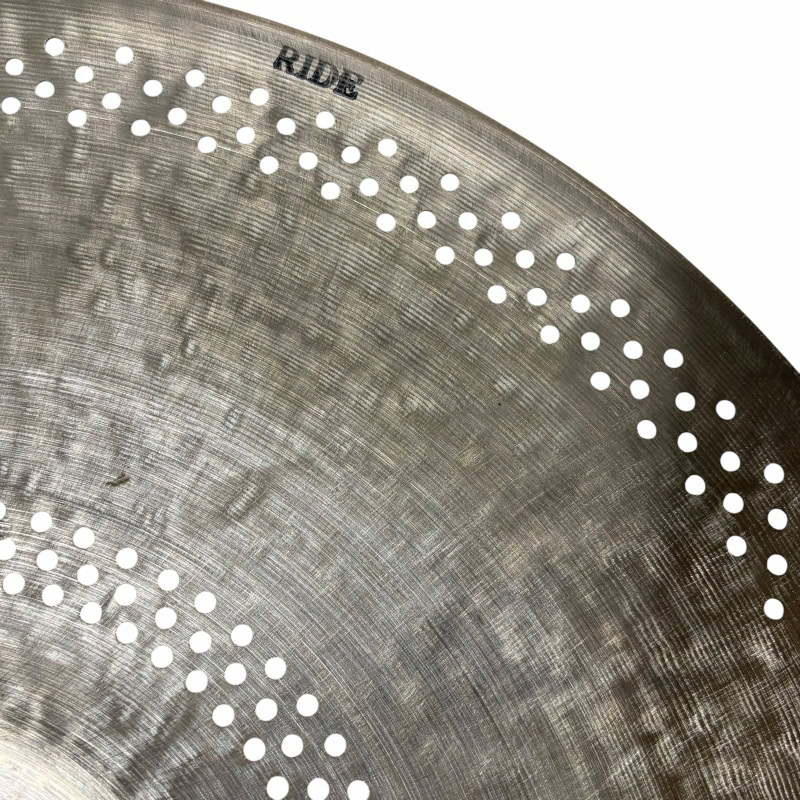 A close-up of a Ride cymbal with perforations and the word 'RIDE' engraved.