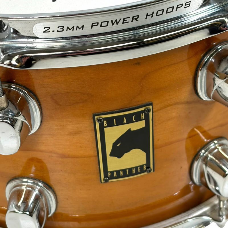 Close-up of Mapex Black Panther Cherry/Maple snare drum with logo.