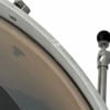 Close-up of a drum shell with hardware and stand in background.