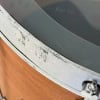 Close-up of a drum with a damaged metal rim and wooden shell.