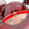 Red acrylic drum shells with chrome hardware for professional drum setup.