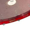 Close-up of a red acrylic drum shell with hardware and scratches.