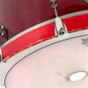 Close-up of a red acrylic drum shell with hardware details.