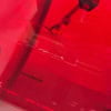 Red acrylic drum shell pack with hardware and drumsticks inside a transparent case.