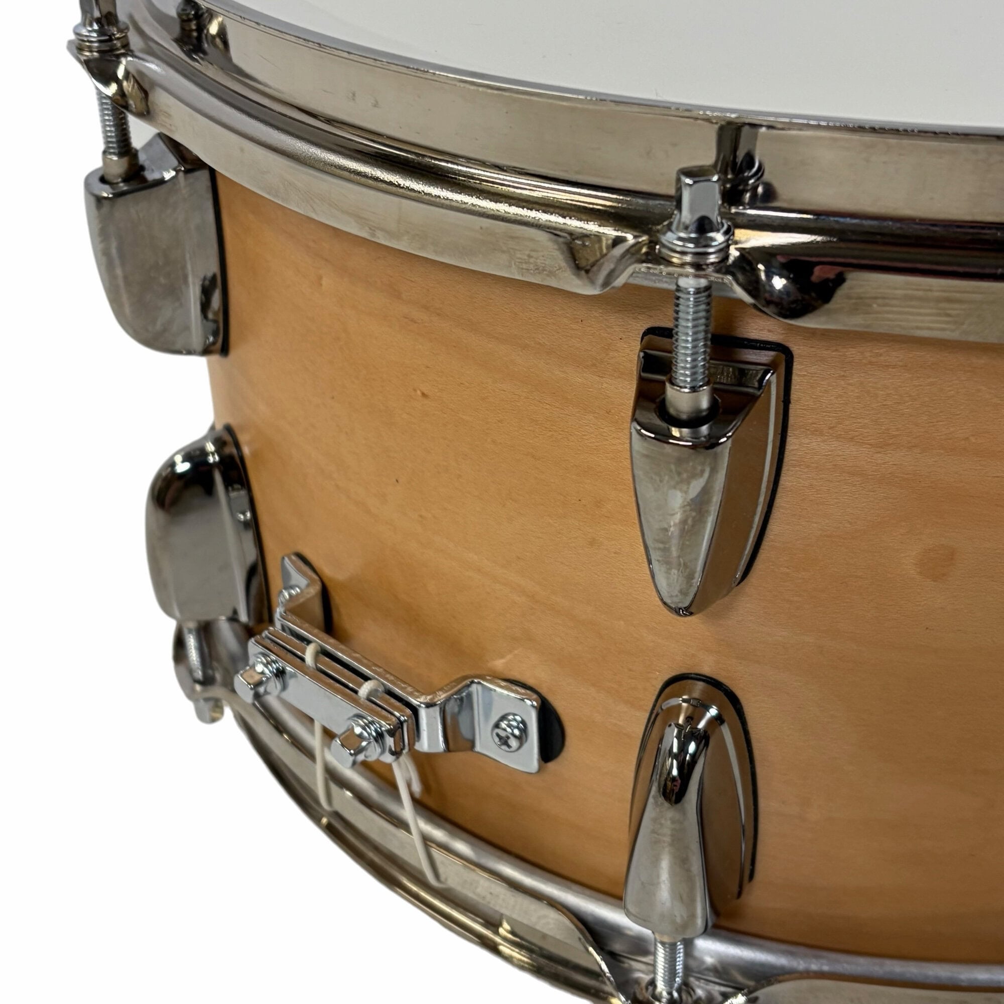 Close-up view of a natural wood snare drum with chrome hardware and lugs.