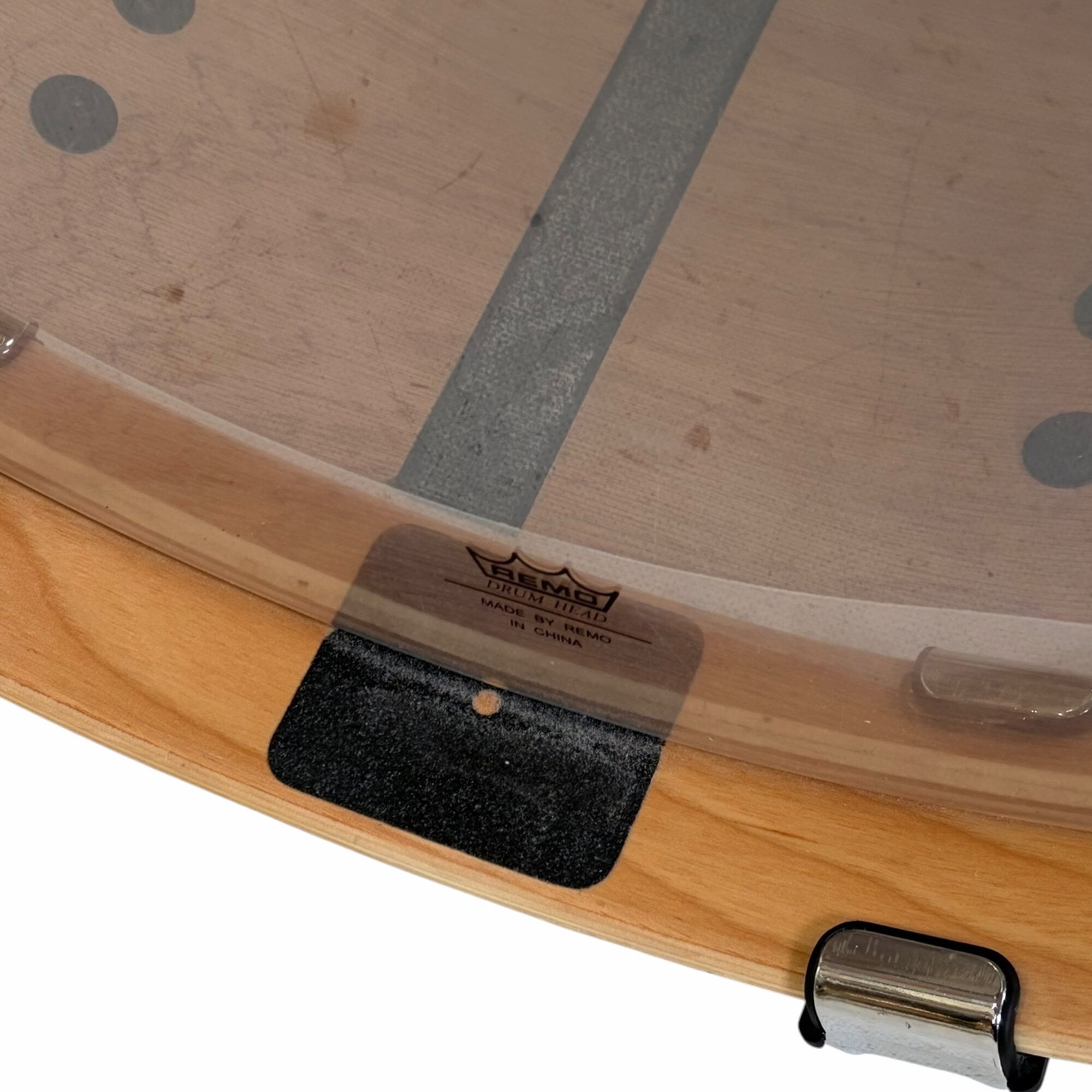 Close-up of drum shell with pad and metal hardware on wooden rims.