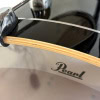 Pearl drum shell close-up with logo and natural wood edge.