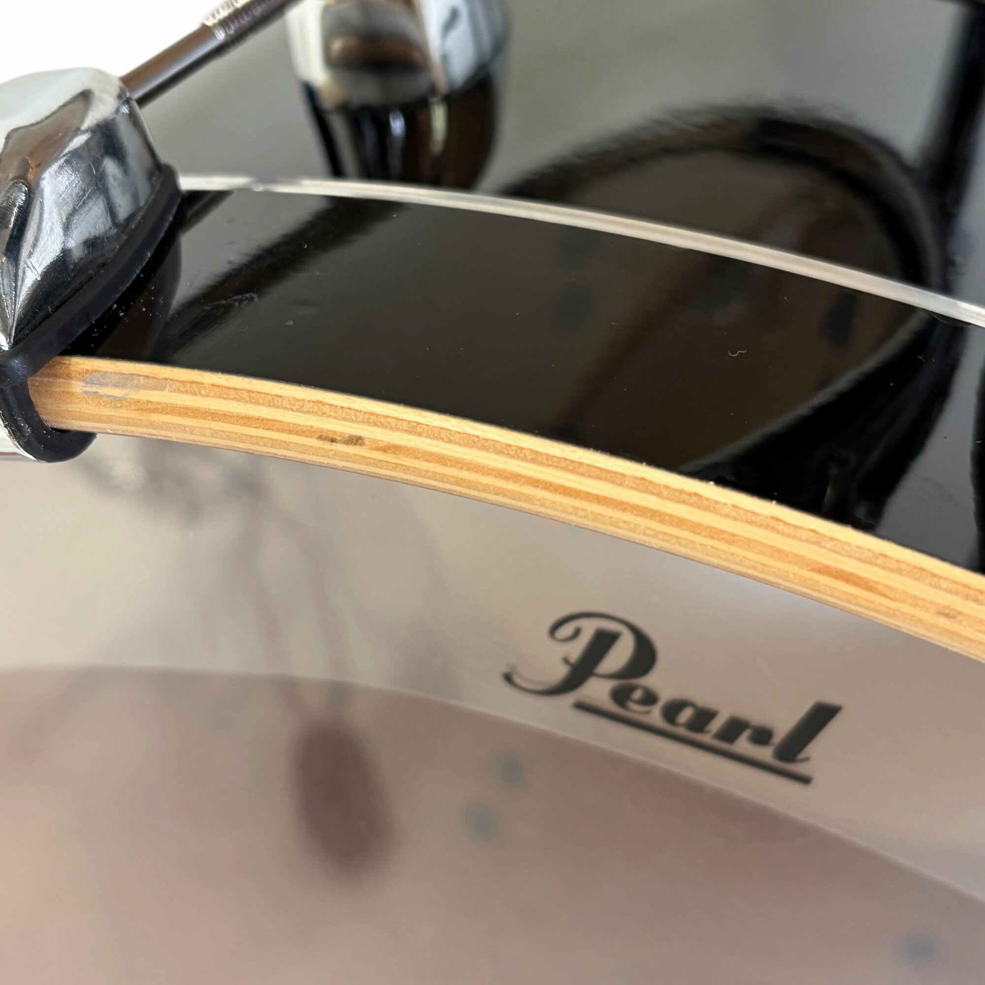 Pearl drum shell close-up with logo and natural wood edge.